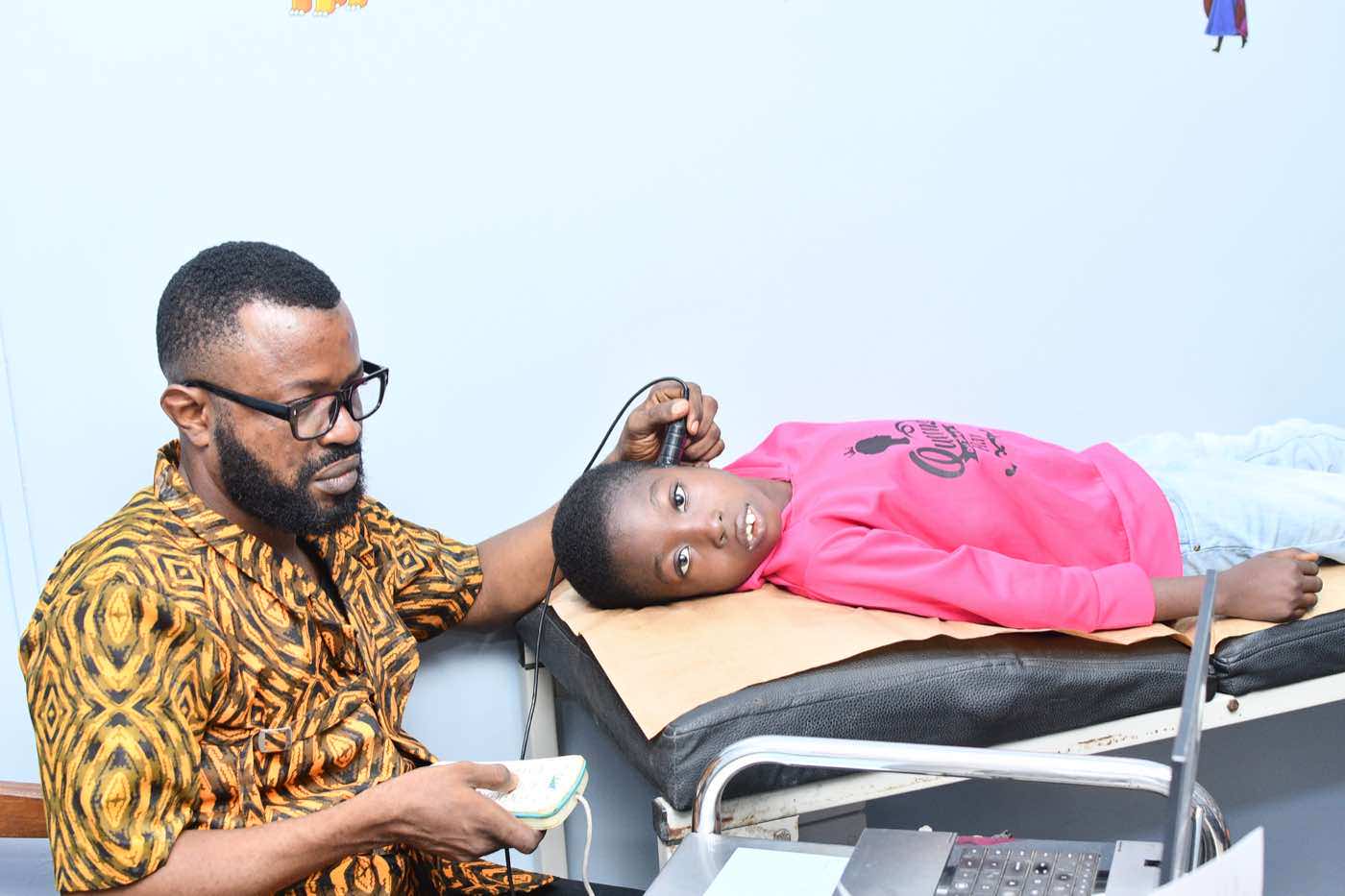 Healthcare worker screening a child with transcranial Doppler support.